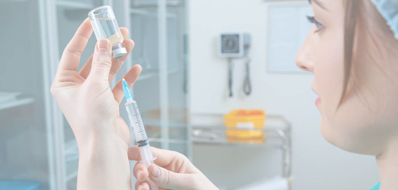 Женщина в больничной форме набирает лекарственный раствор